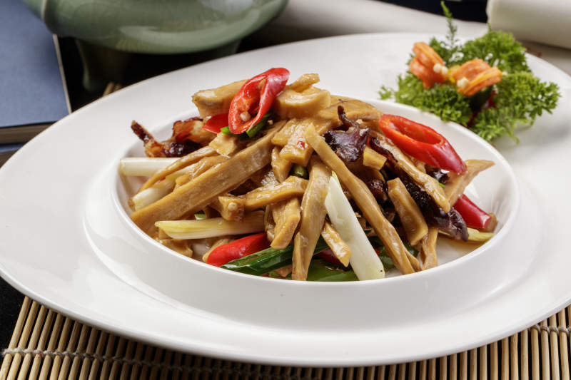 白色瓷盘装的的大葱烧猪肚