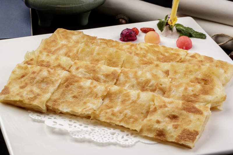 方形瓷盤裝的印度飛餅擺放在樟木砧板上