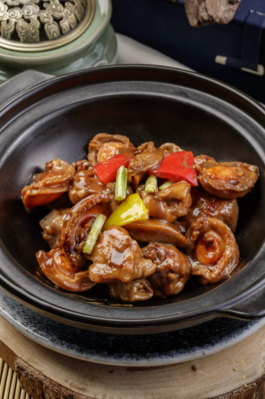 黑色砂锅装的砂锅鲍鱼鸡块摆放在樟木砧板上