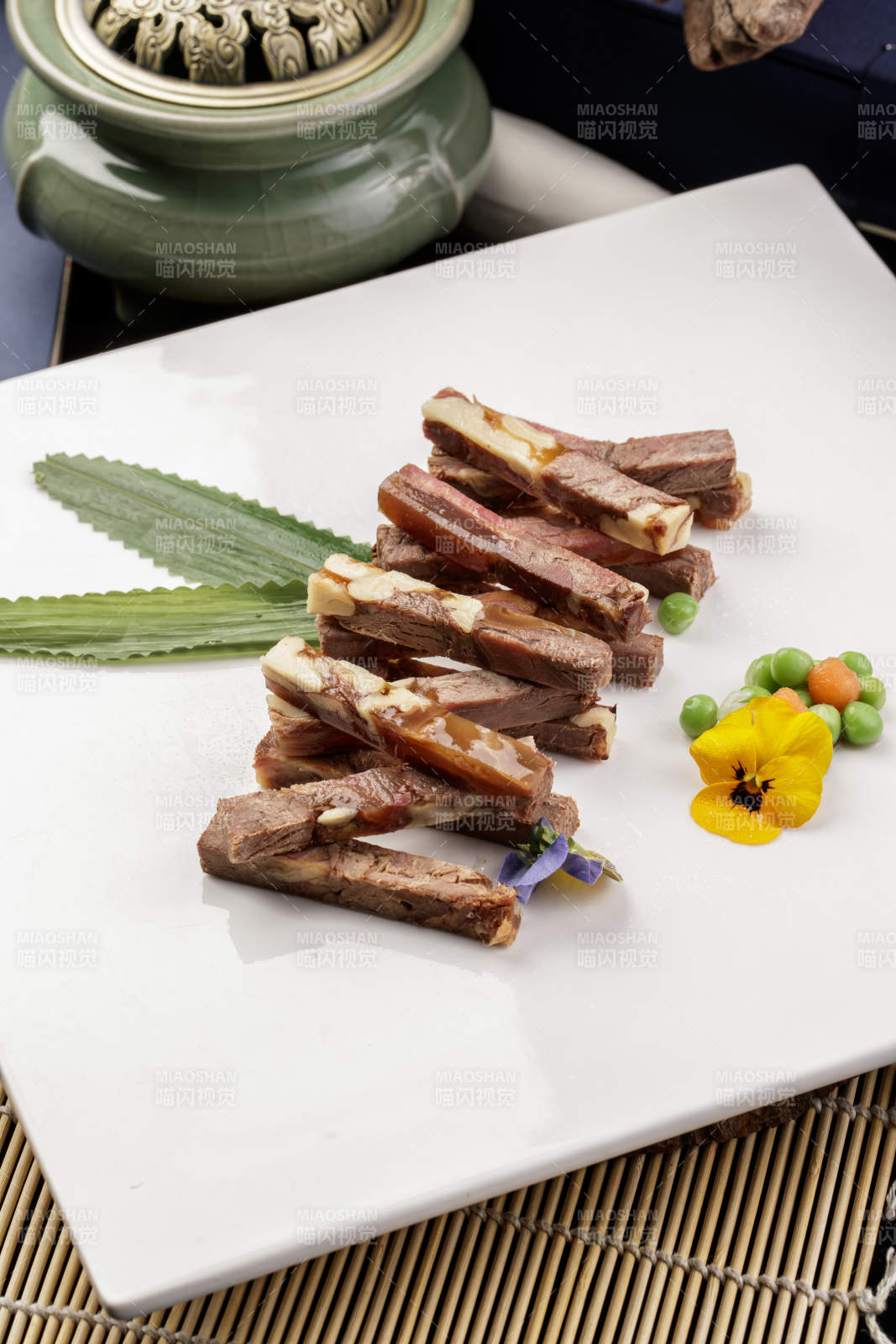 方形瓷盘装的桃仁水晶驴肉摆放在寿司帘上