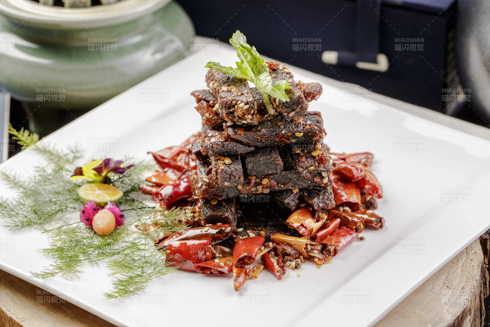 方形瓷盘装的麻辣牛肉摆放在樟木砧板上