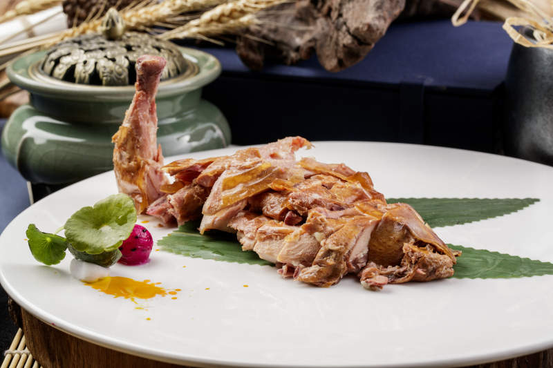 白色圆瓷盘装的风味手撕鸡摆放在樟木砧板上图片