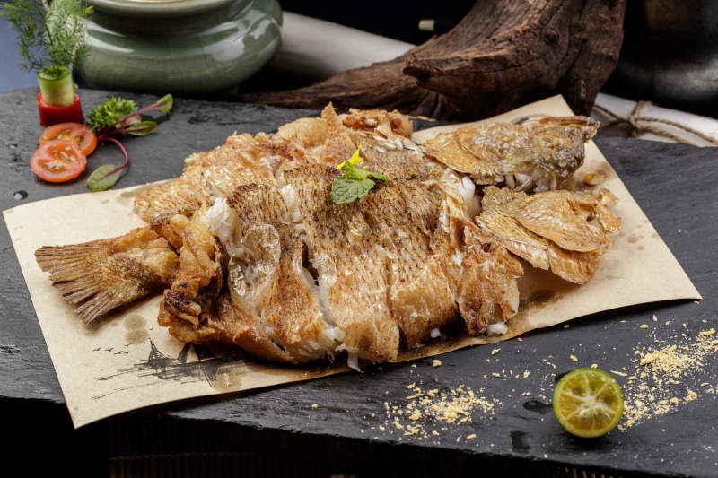 香酥炸高背鯽魚擺放在黑色背景上