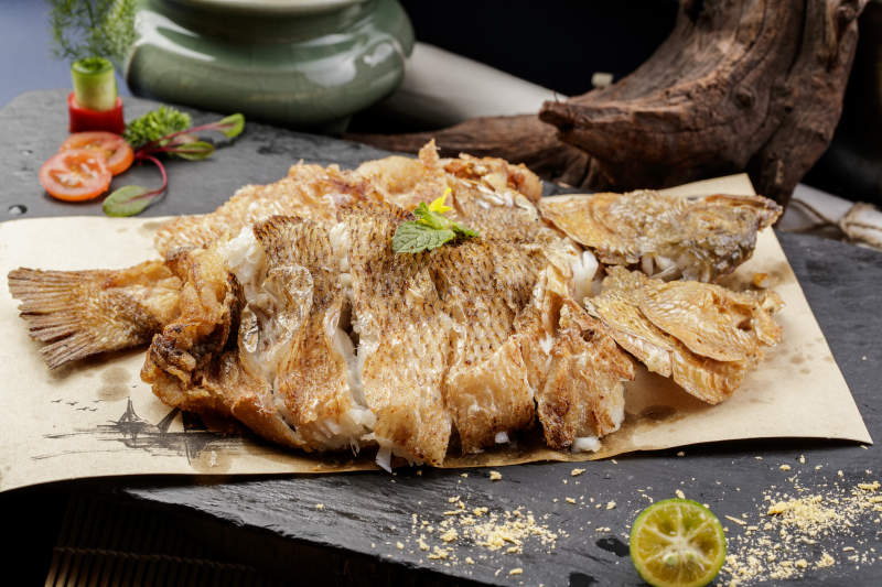 香酥炸高背鯽魚擺放在黑色背景上