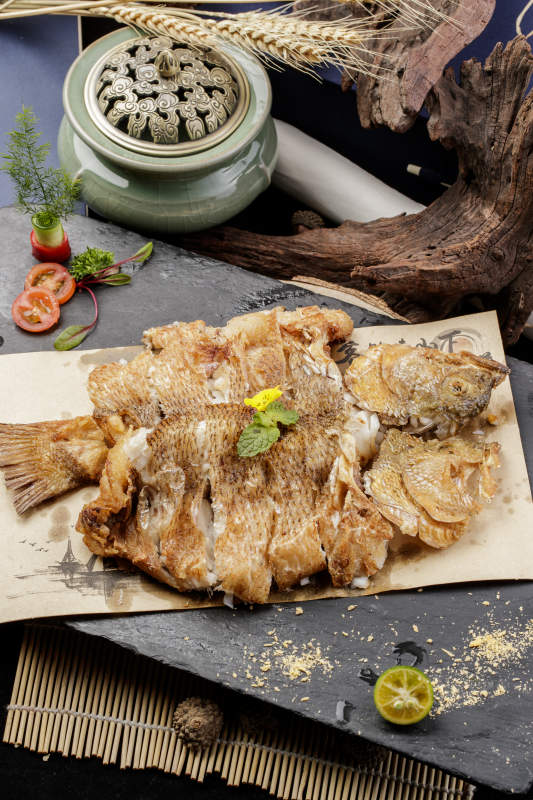 香酥炸高背鯽魚擺放在黑色背景上
