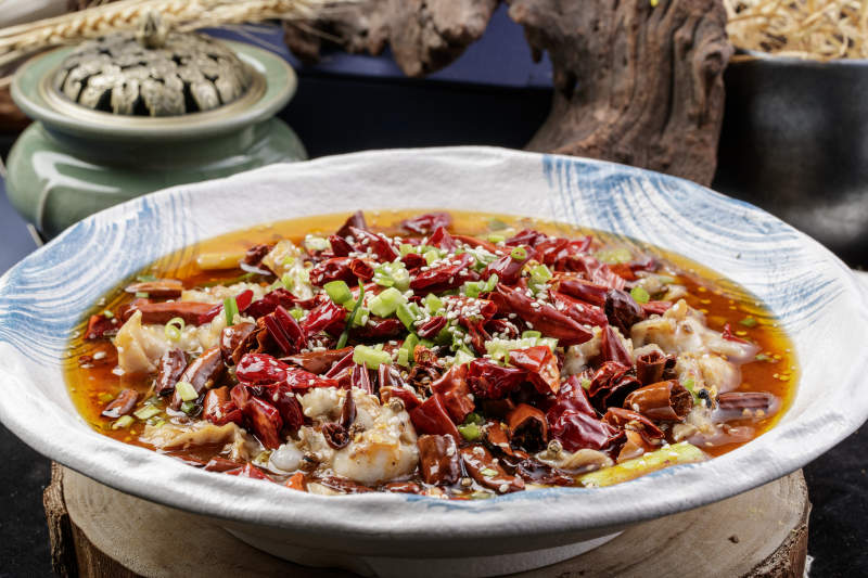 白色花紋盤裝的香辣饞嘴蛙擺放在壽司簾上