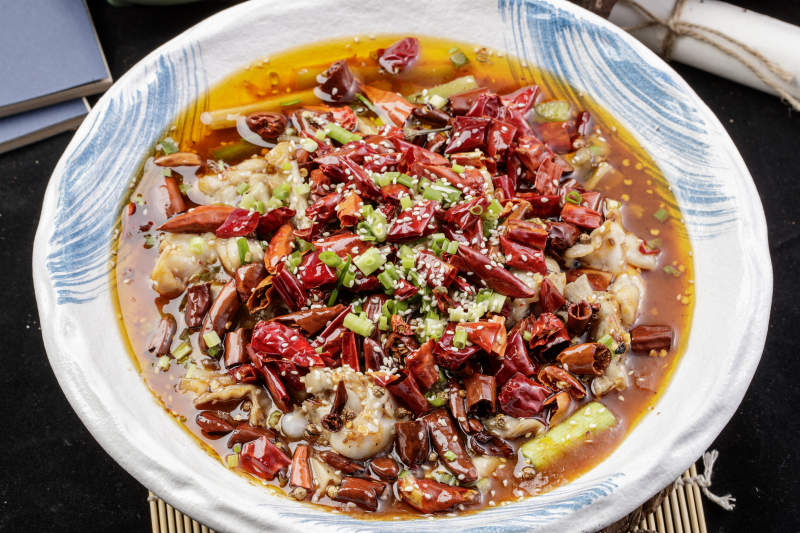 白色花紋盤裝的香辣饞嘴蛙擺放在壽司簾上