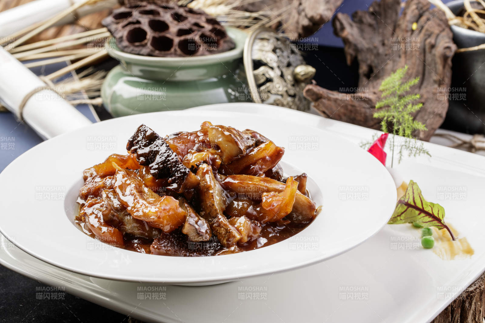 圆形白瓷盘装的葱烧梅花参摆放在黑色背景上