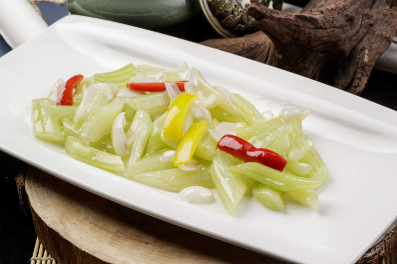 长方形瓷盘装的西芹炒百合摆放在樟木砧板上