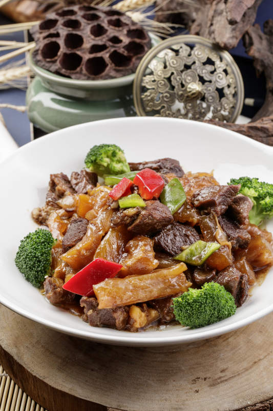 白色耳盘装的牛五花烧蹄筋摆放在樟木砧板上