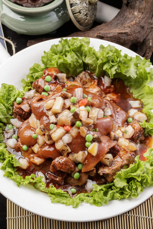 圆形瓷盘装的红扒大肘子摆放在樟木砧板上