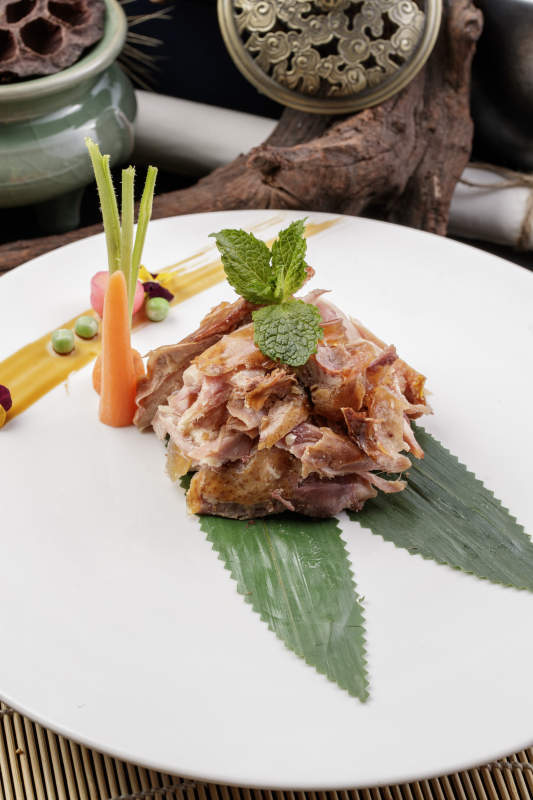 圆形白瓷盘装的风味手撕鸡摆放在寿司帘上