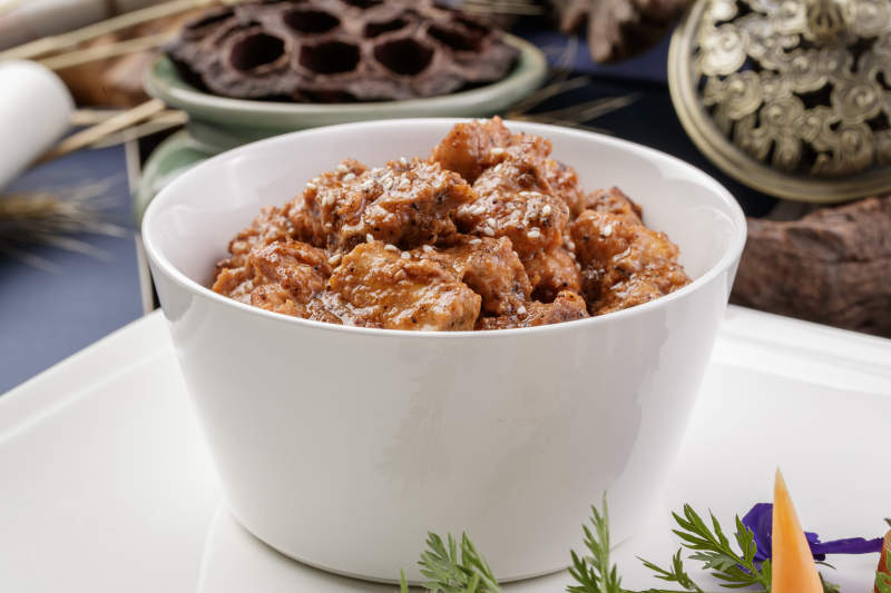 白色瓷碗装的黑胡椒猪小排摆放在黑色背景上