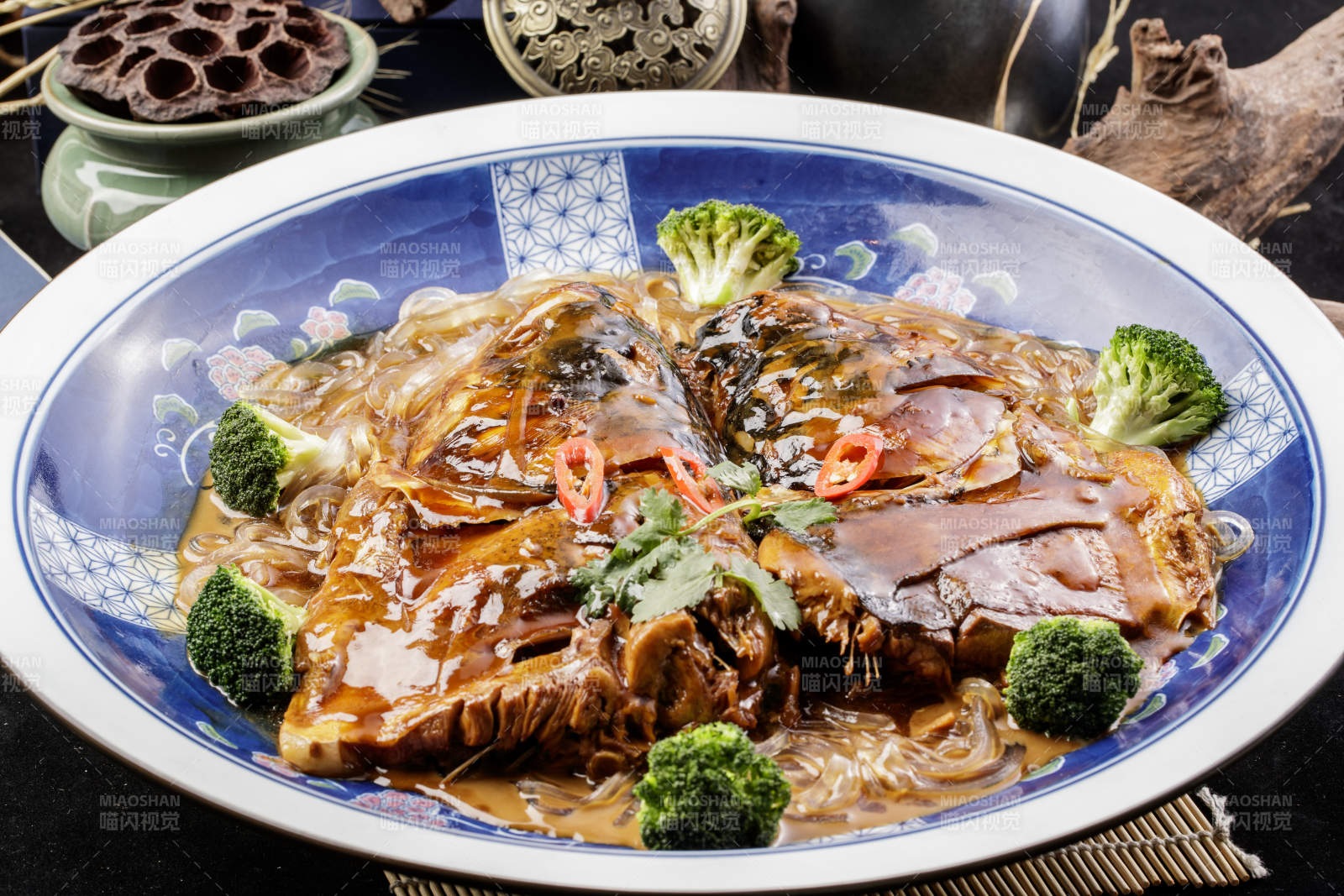 青花瓷盘装的垮炖大鱼头摆放在寿司帘上