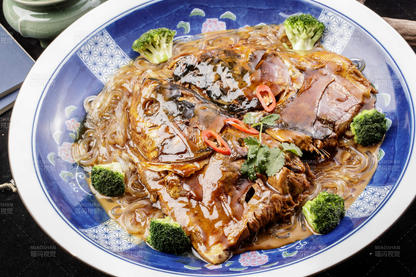 青花瓷盘装的垮炖大鱼头摆放在寿司帘上