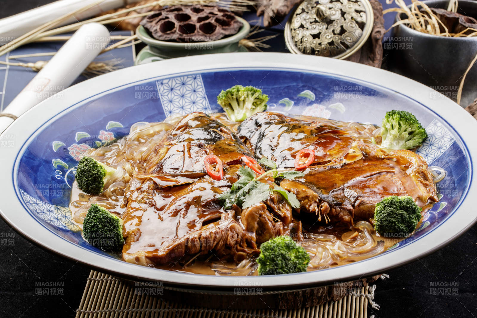 青花瓷盘装的垮炖大鱼头摆放在寿司帘上