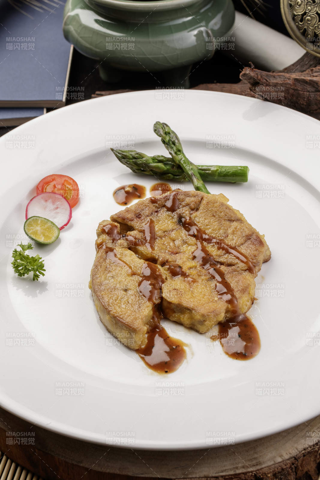 白色圆形瓷盘装的香煎法式鹅肝摆放在樟木砧板上