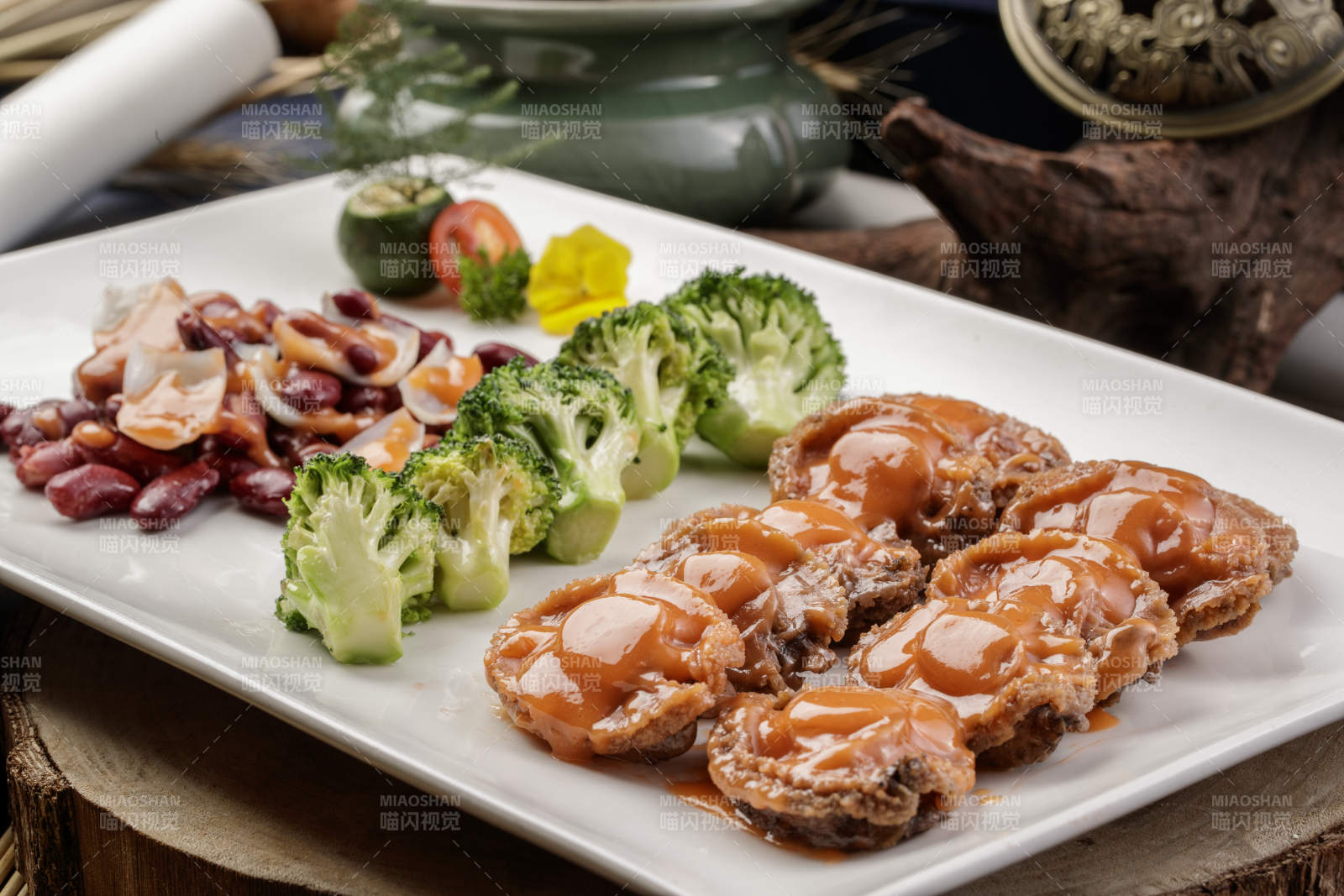 长方形瓷盘装的百合红豆浓汁薏米鲜鲍鱼摆放在樟木砧板上