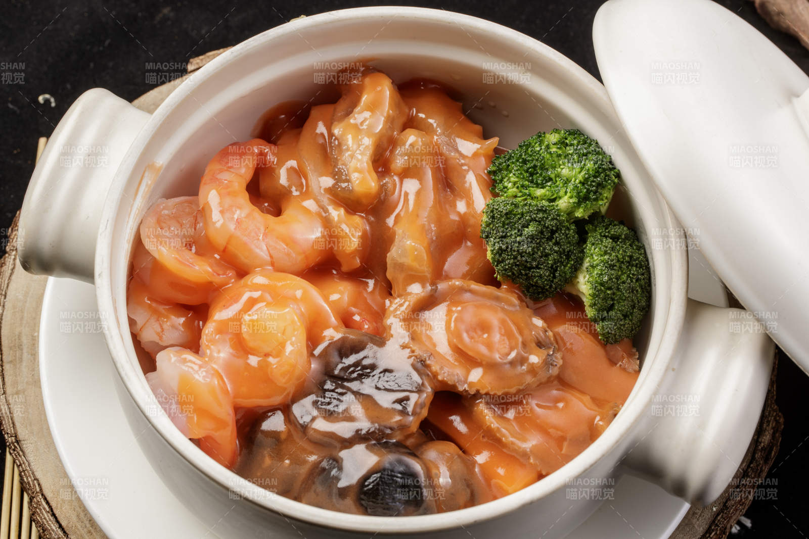 白色瓷砂锅装的浓汤海鲜煲摆放在寿司帘
