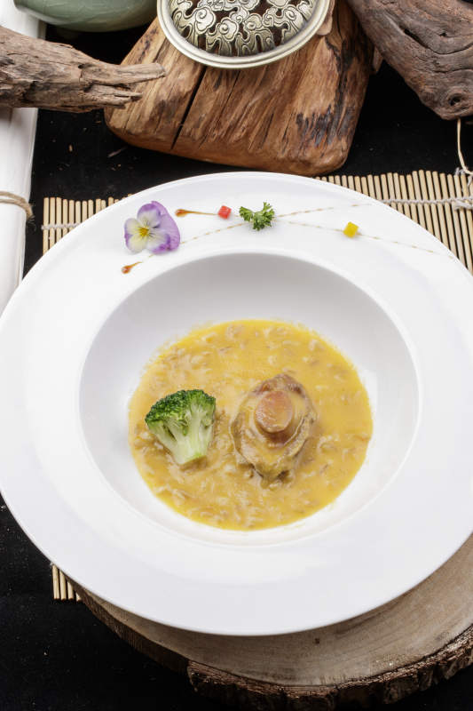 圆形白瓷盘装的薏米鲍鱼羹摆放在樟木砧板上