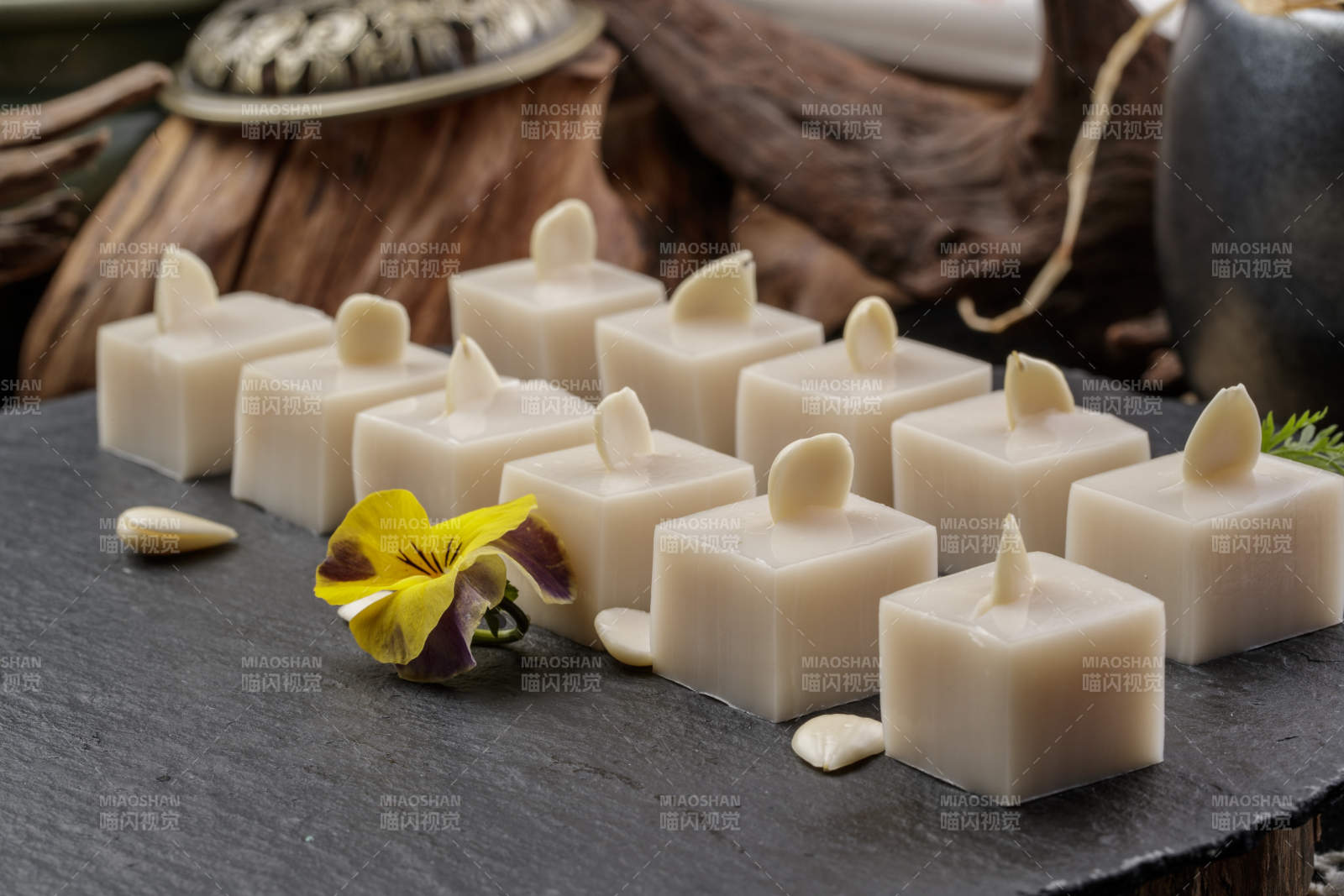 圆形黑色石盘装的奶香杏仁糕摆放在寿司帘上