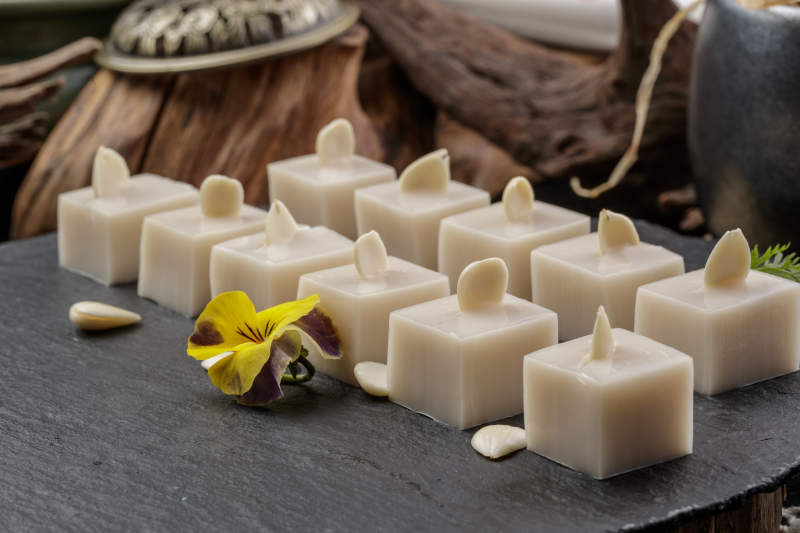 圆形黑色石盘装的奶香杏仁糕摆放在寿司帘上