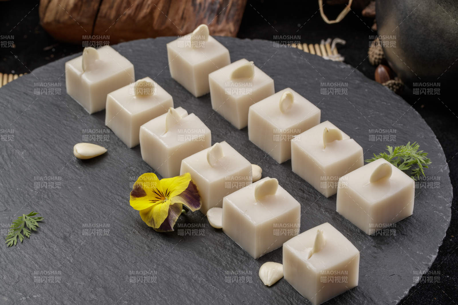 圆形黑色石盘装的奶香杏仁糕摆放在寿司帘上