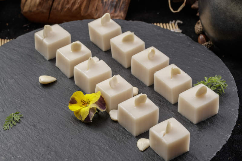 圆形黑色石盘装的奶香杏仁糕摆放在寿司帘上