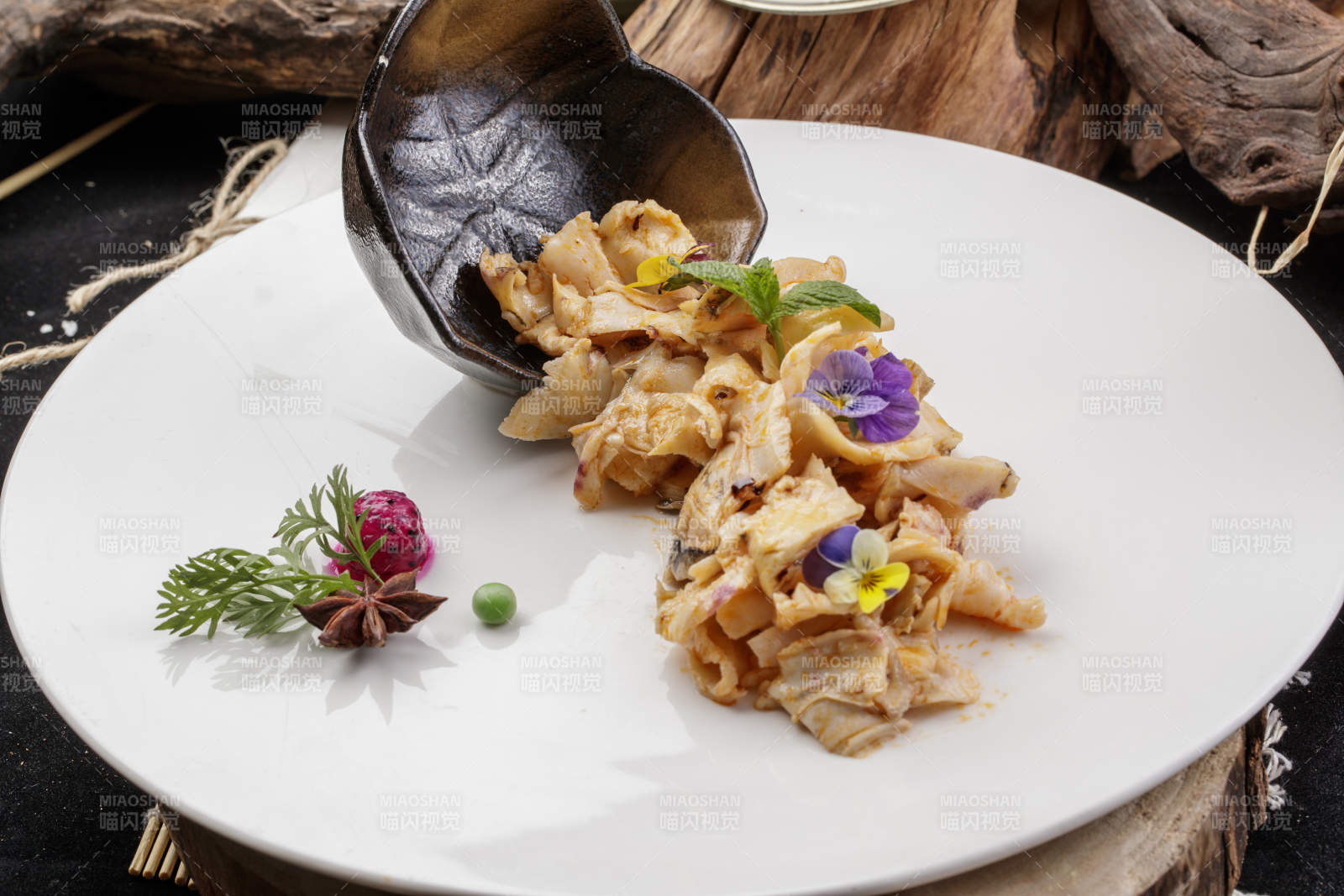 圓形瓷盤裝的溫拌海螺片擺放在壽司簾上