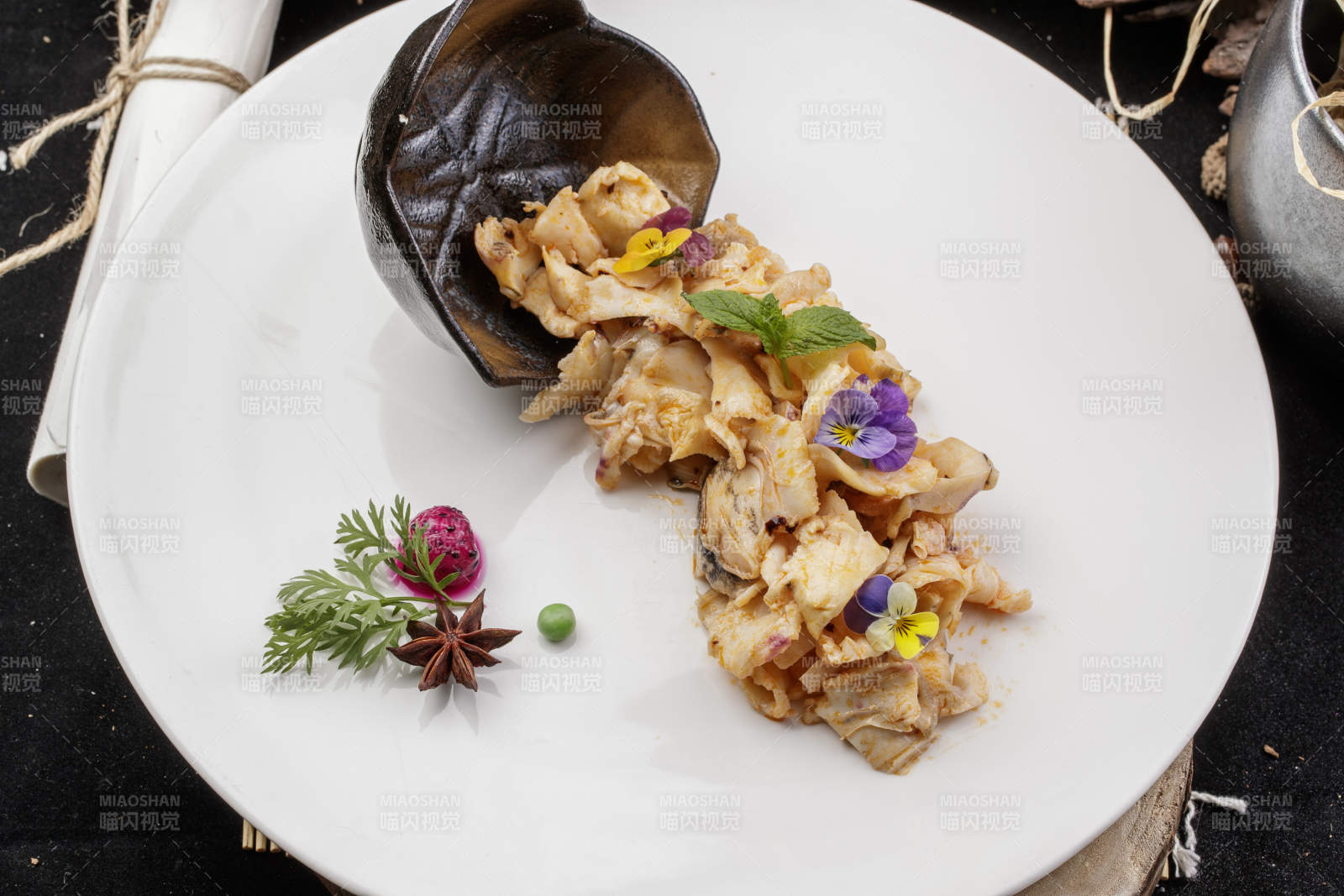 圓形瓷盤裝的溫拌海螺片擺放在壽司簾上