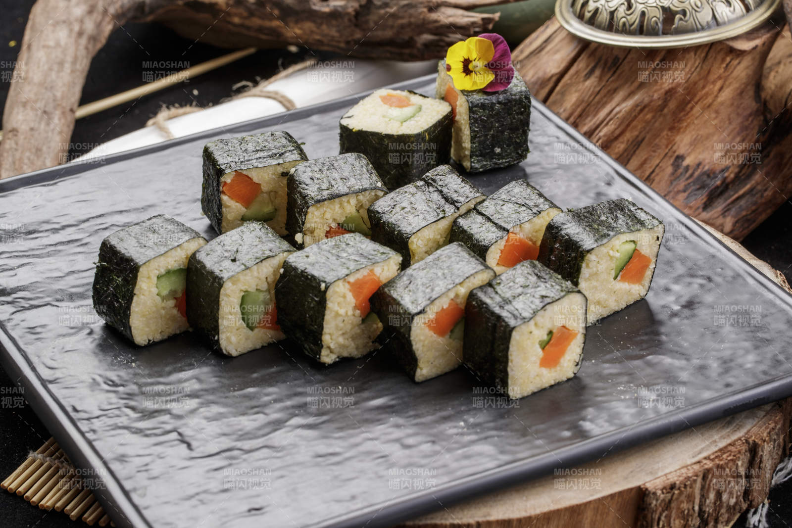 黑色石盘装的小米寿司卷摆放在樟木砧板上