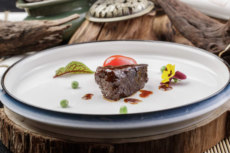 圆形瓷盘装的一品雪花和牛摆放在寿司帘上