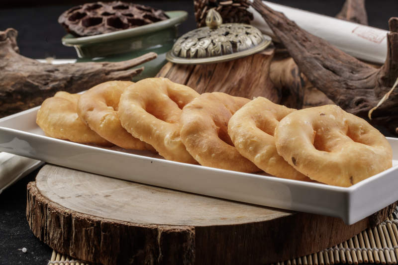 长方形瓷盘装的香炸小油饼摆放在樟木砧板上