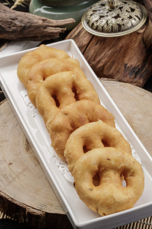 长方形瓷盘装的香炸小油饼摆放在樟木砧板上