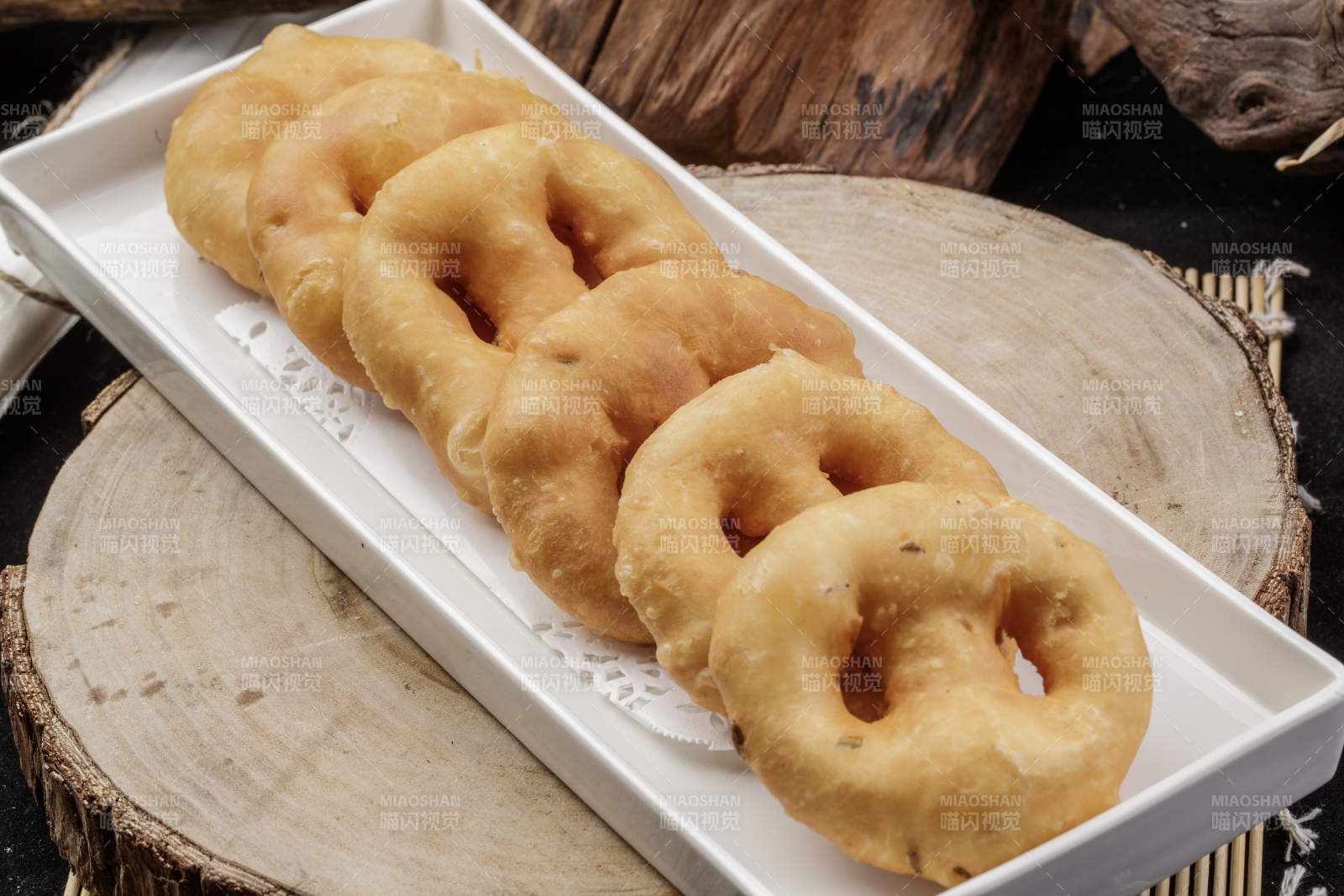 长方形瓷盘装的香炸小油饼摆放在樟木砧板上