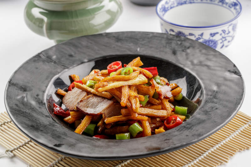 黑色石盘装的菜菔炒腊肉