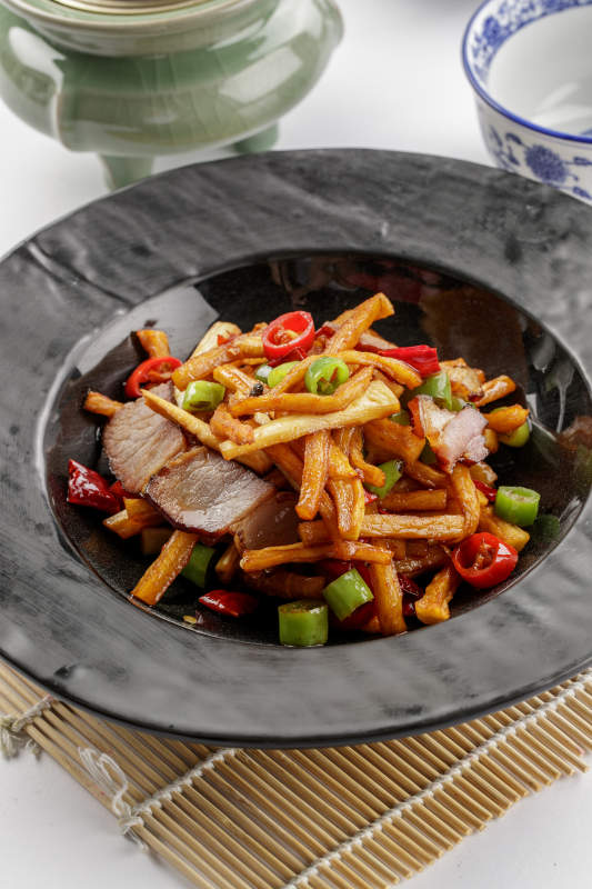 黑色石盘装的菜菔炒腊肉