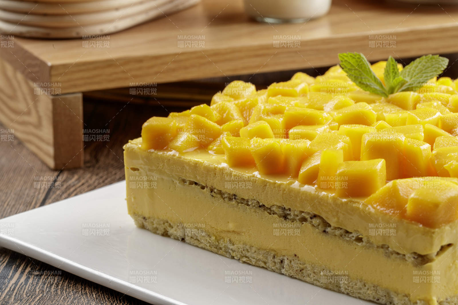 芒果奶油三层蛋糕摆放在木纹底板上