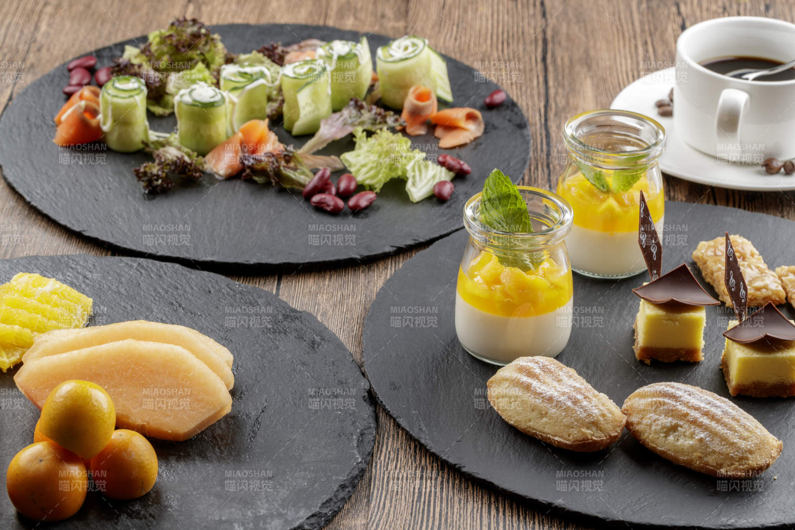 圆形黑色石板装的甜品全拼摆放在黑色背景上