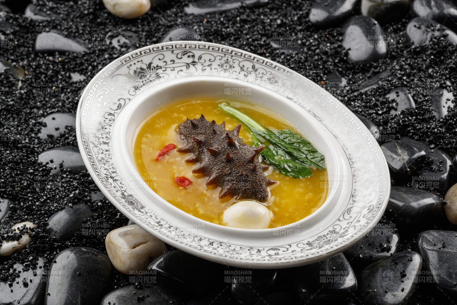 小米炖辽参摆放在黑色鹅卵石上-摄影图