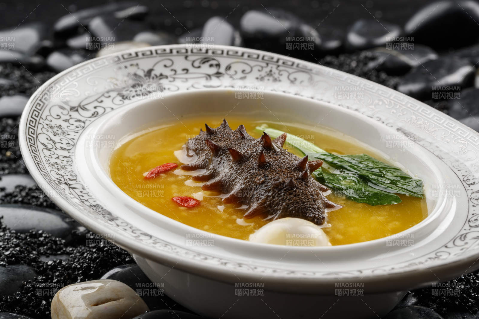 小米炖辽参摆放在黑色鹅卵石上-摄影图