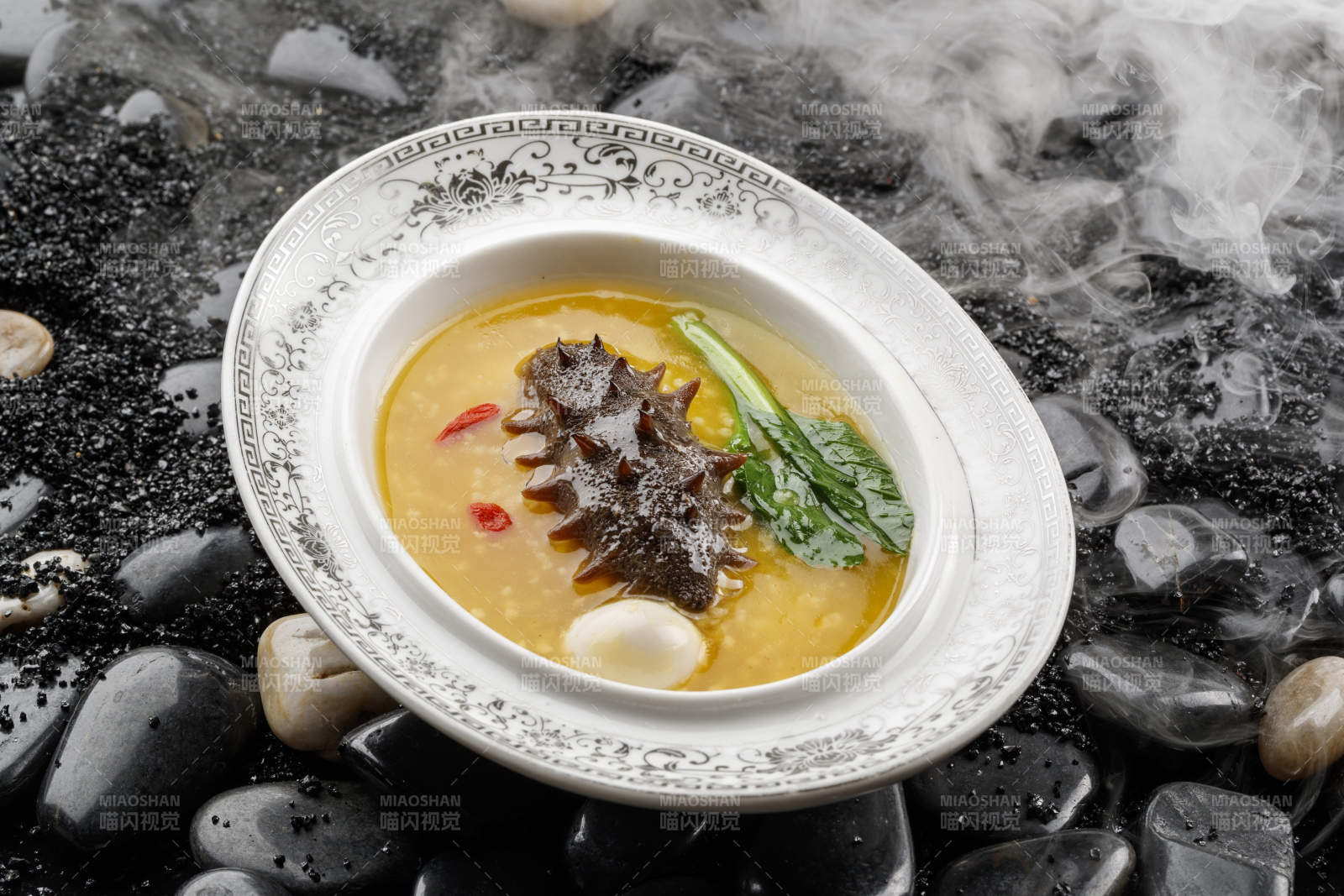 小米炖辽参摆放在黑色鹅卵石上-摄影图