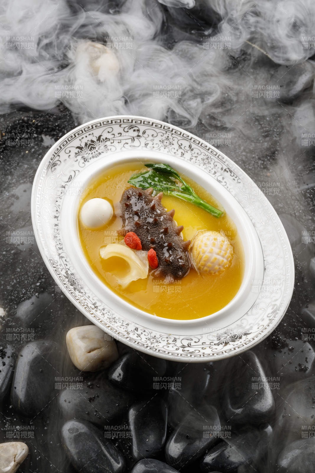 小米炖辽参摆放在黑色鹅卵石上-摄影图