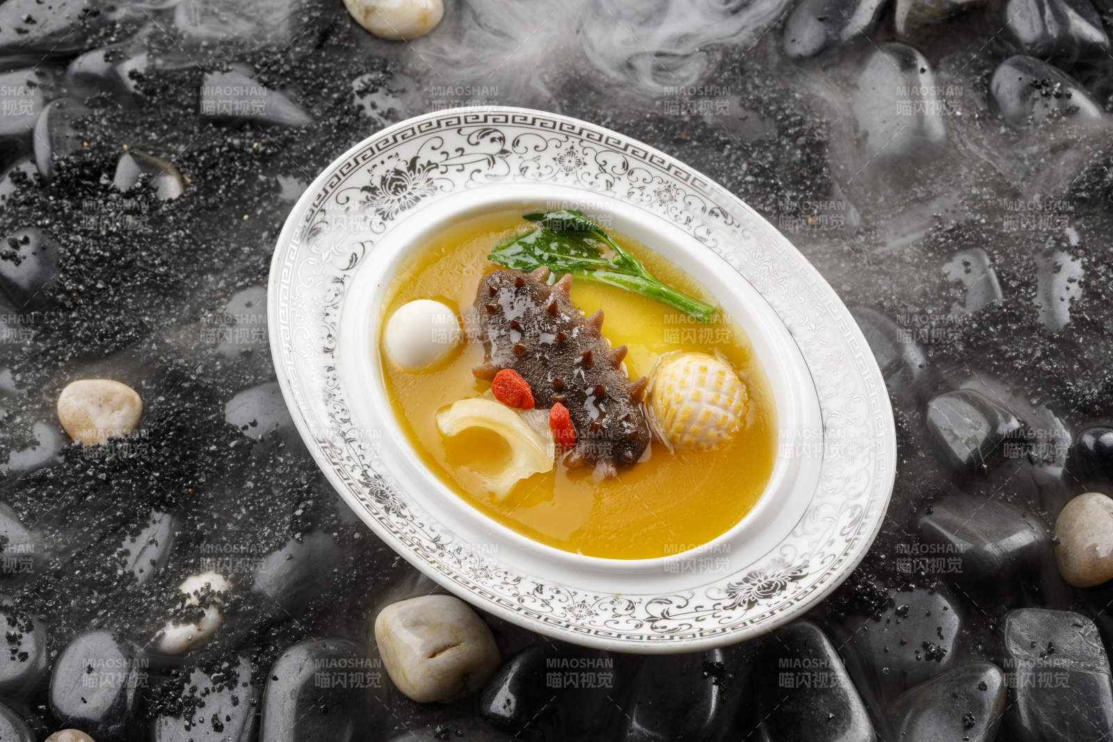 小米炖辽参摆放在黑色鹅卵石上-摄影图