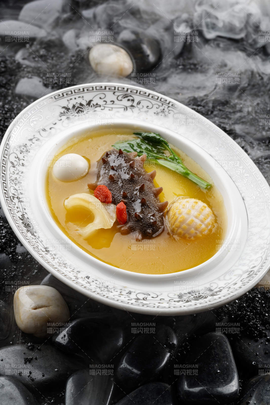 小米炖辽参摆放在黑色鹅卵石上-摄影图