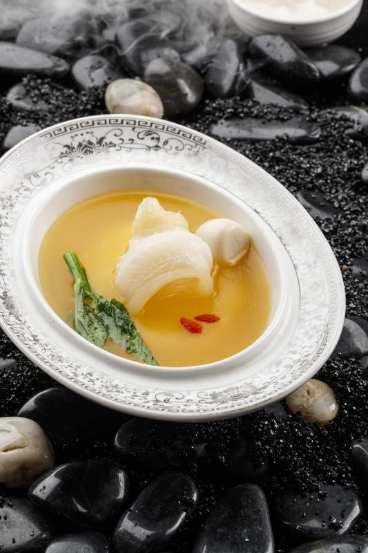 浓汤鱼唇摆放在干冰缭绕的鹅卵石上