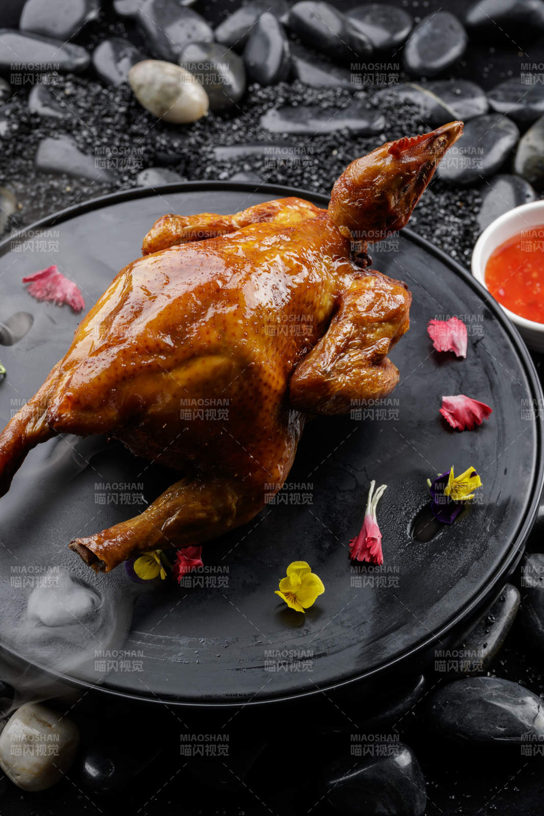 黑色底盘装的港式脆皮鸡摆放在黑色鹅卵石上