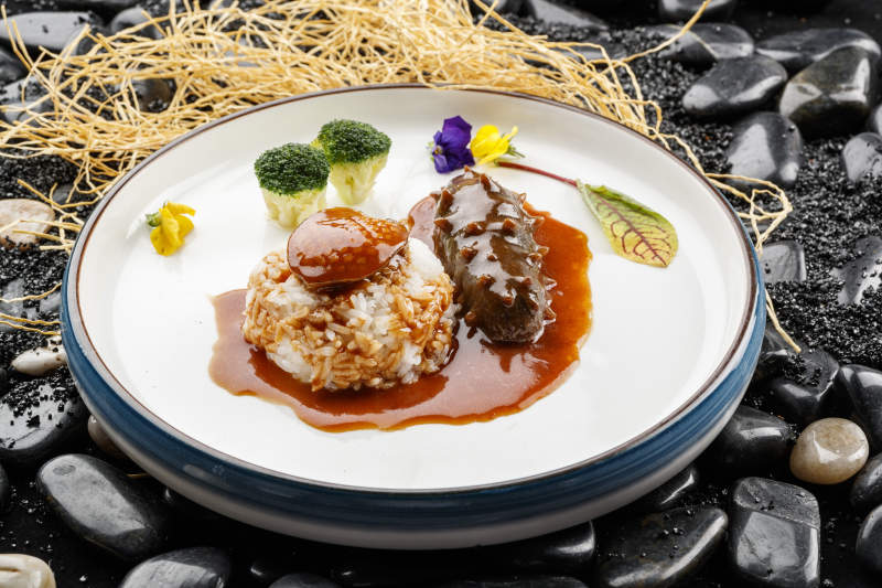 鮮鮑魚(yú)遼參撈飯擺放在黑色鵝卵石上