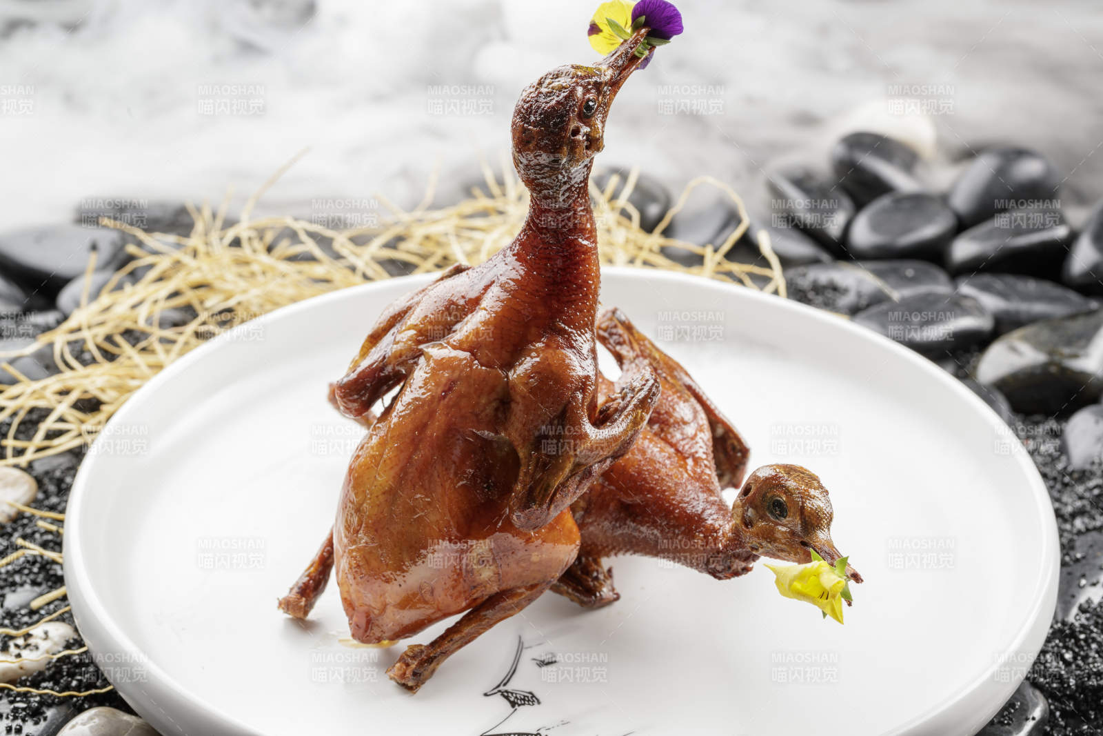 白色圆盘装的生炸乳鸽摆放在黑色鹅卵石上