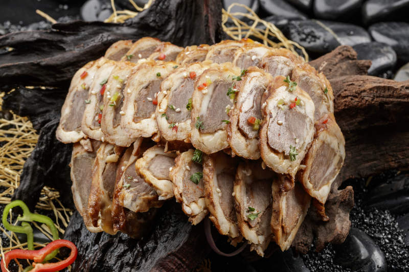 崖柏根装的蒙古烤羊里脊摆放在黑色鹅卵石上